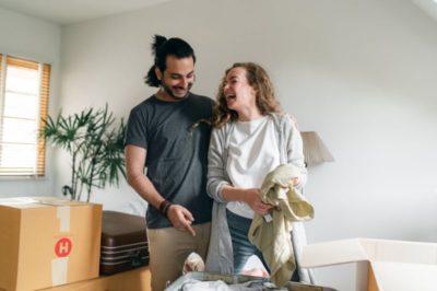 excited couple unpacking boxes in new apartment