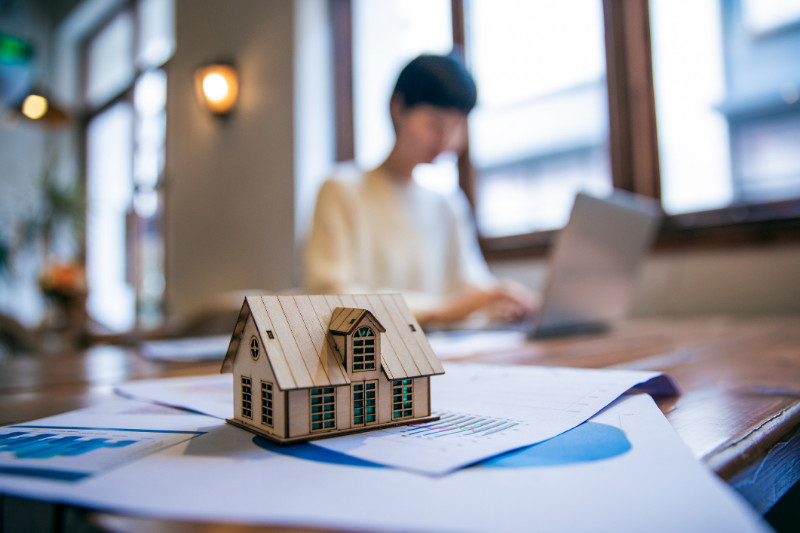 Real Estate Agent Working On Laptop and a small house model